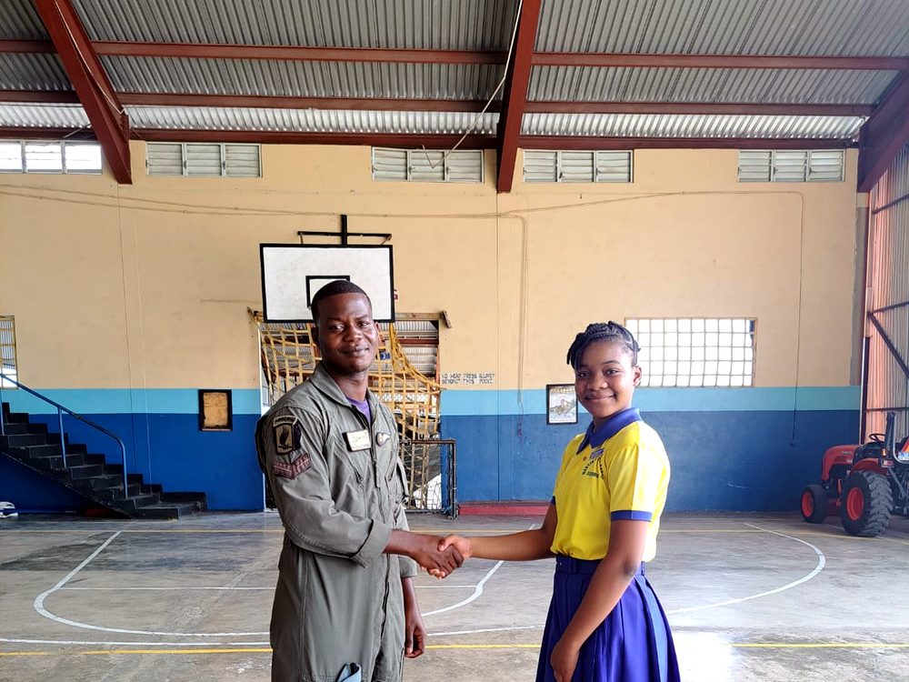 A pupil shaking hands with a Jamaica Defence Force airman